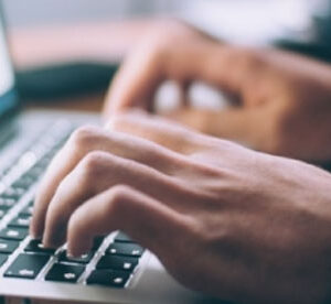 Person typing on a laptop, working on NTS exam preparation.